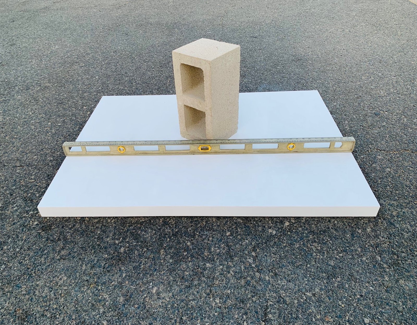 Wood artist panel flatness test — cinder block resting on gessoed 35x48 panel with level showing flush surface